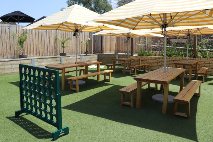 Outdoor seating with yellow-striped umbrellas and a giant Connect Four game.