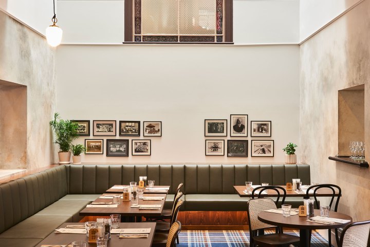 Stylish cafe with framed photos, green bench seating, and wooden tables.
