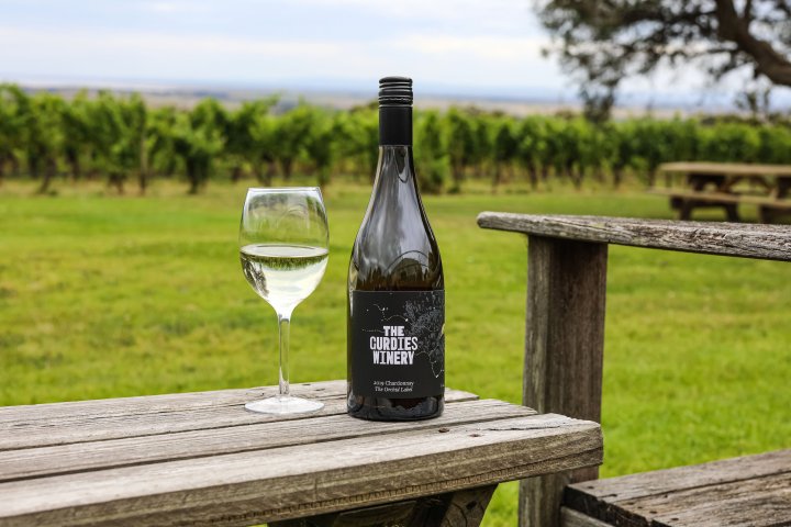 a glass of wine sitting on top of a wooden bench