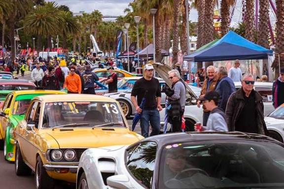 a group of people walking down a street next to a car
