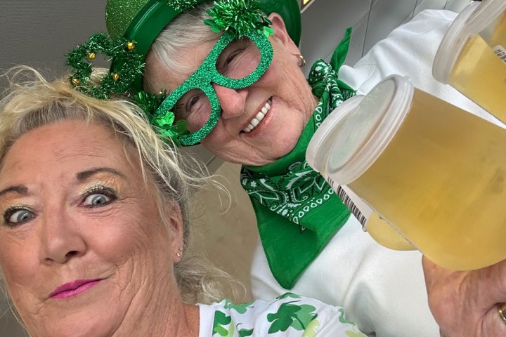 Two people with St. Patrick's Day attire, holding drinks and smiling.