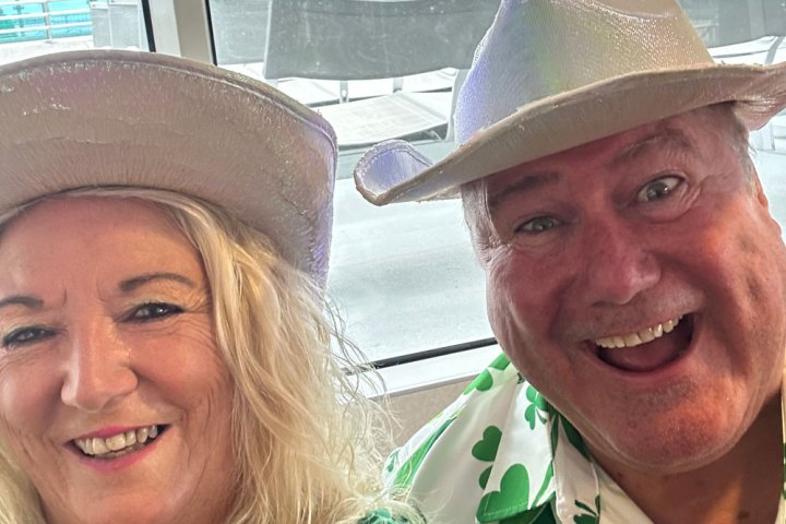 Two smiling people wearing cowboy hats indoors.