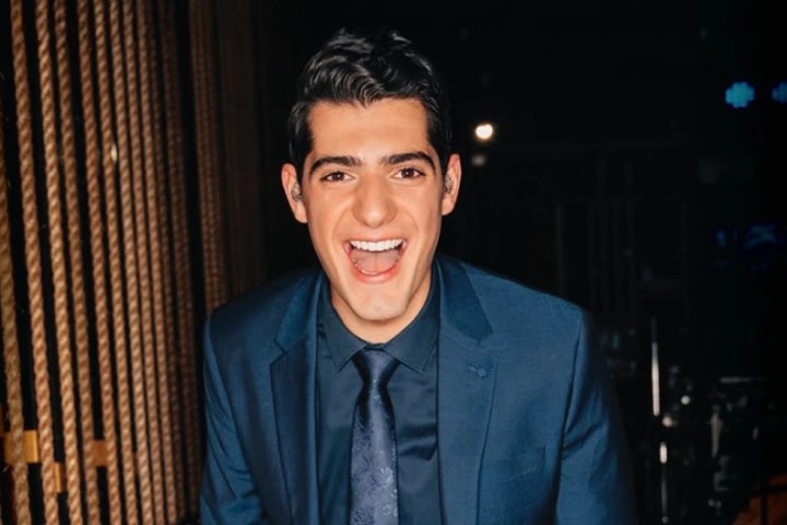 Smiling person in a blue suit with ropes in the background.