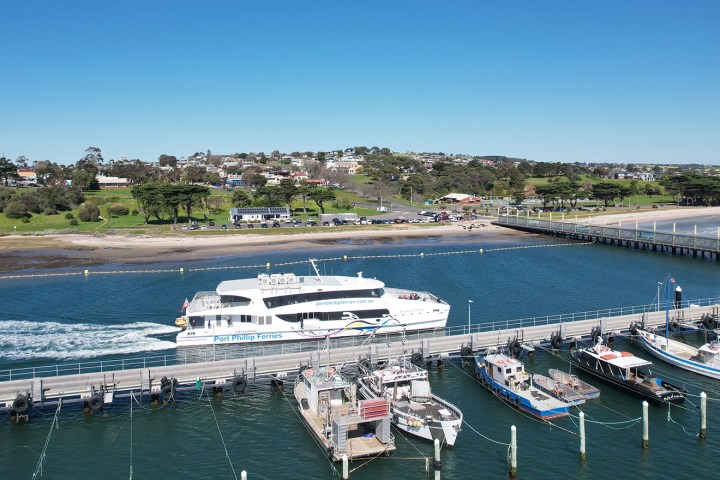 Aerial view of ferry and boats at a dock with a coastal town in the background.