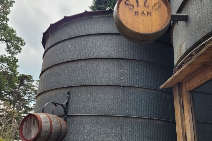 Exterior of Silo Bar, featuring large silo tanks and wooden barrels.