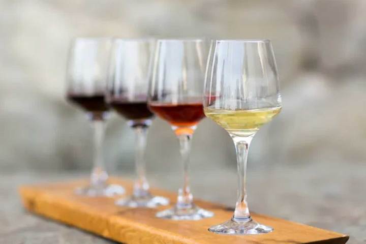 Four wine glasses with different wines on a wooden plank.