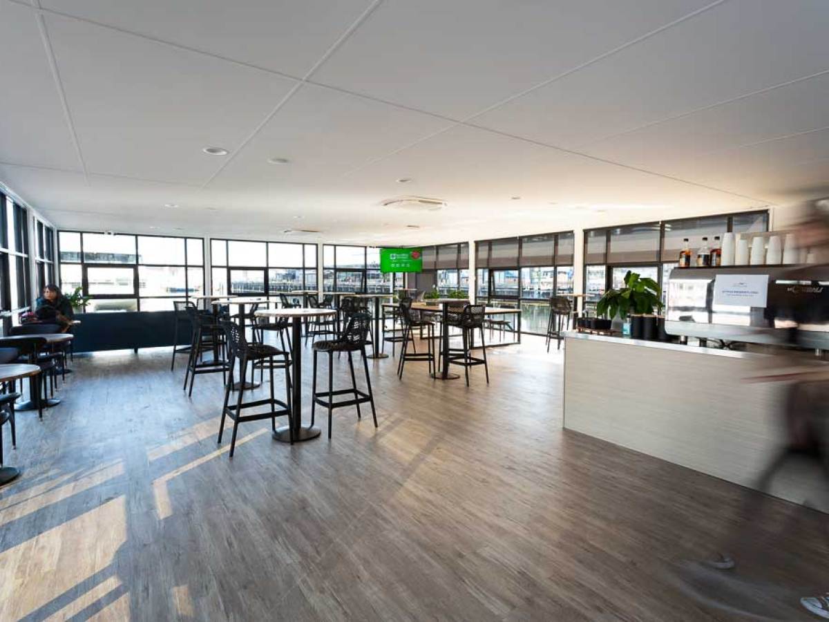 Spacious, modern cafe interior with tables, chairs, and large windows.