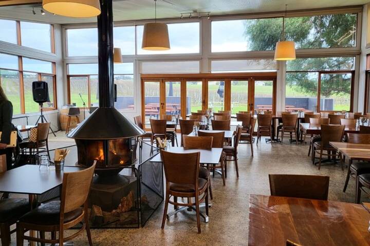 Cozy restaurant with a central fireplace, wooden tables, and large windows.