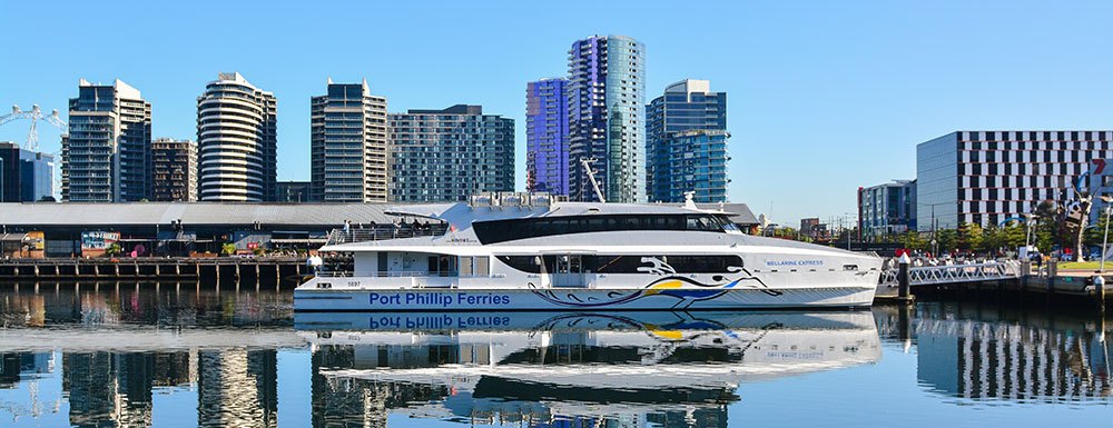 Ferry docked with city skyline background on a clear day.