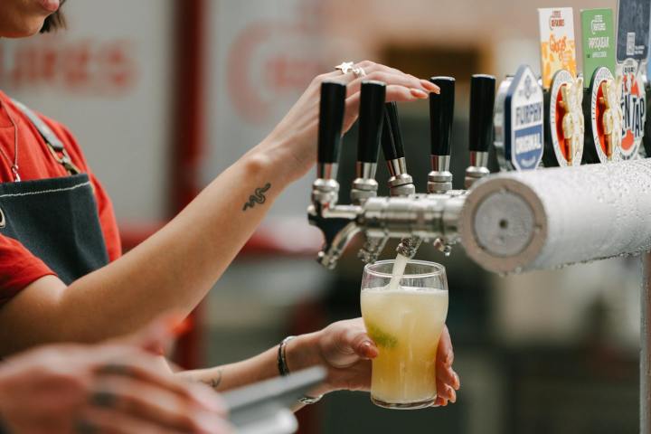 Person pouring beer from a tap into a glass at a bar.