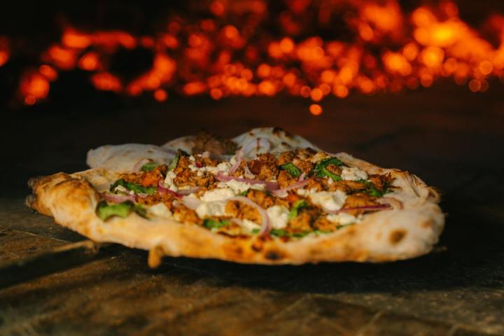 Pizza with toppings baking in a wood-fired oven.