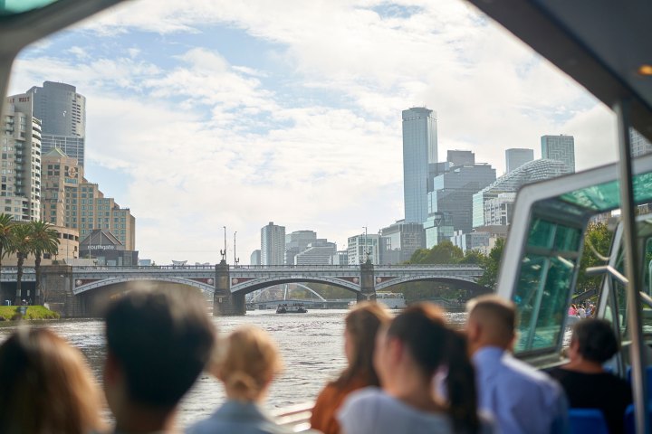 People on a boat looking at a city skyline with bridge.