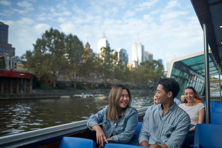 People smiling on a boat with city skyline in the background.