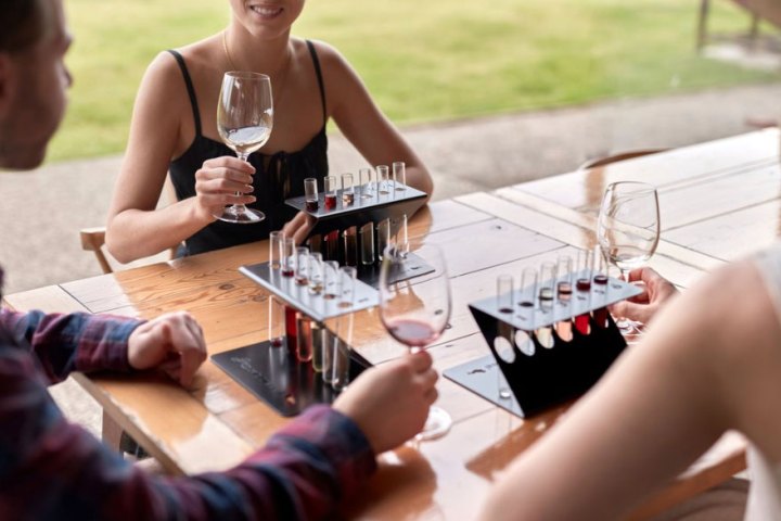 People enjoying wine tasting with glasses and test tubes on a wooden table.