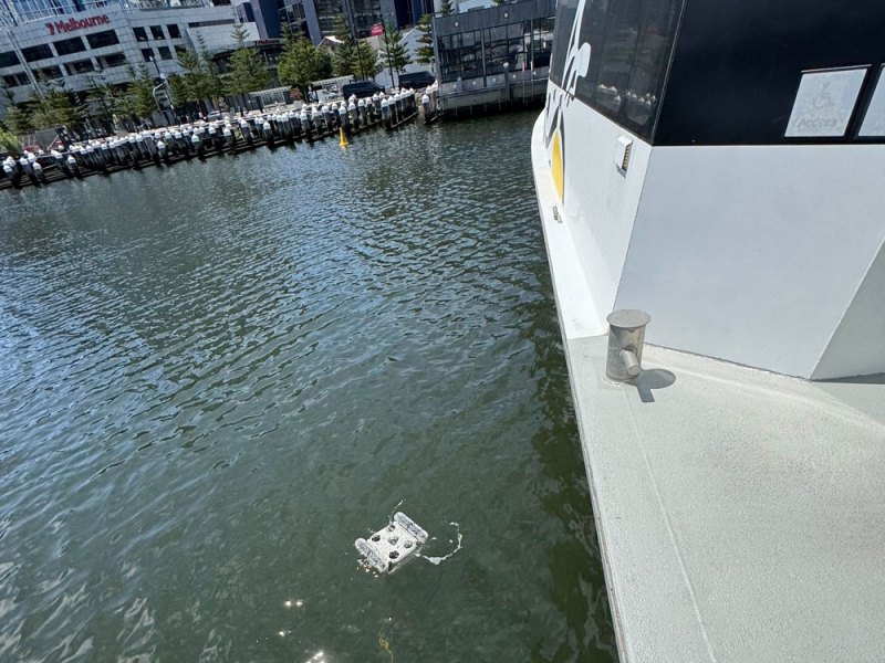 Floating device in water near large boat at dockside.