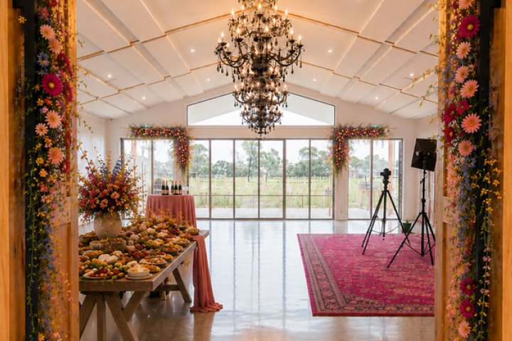 Elegant banquet hall with chandelier, floral decor, and buffet table.