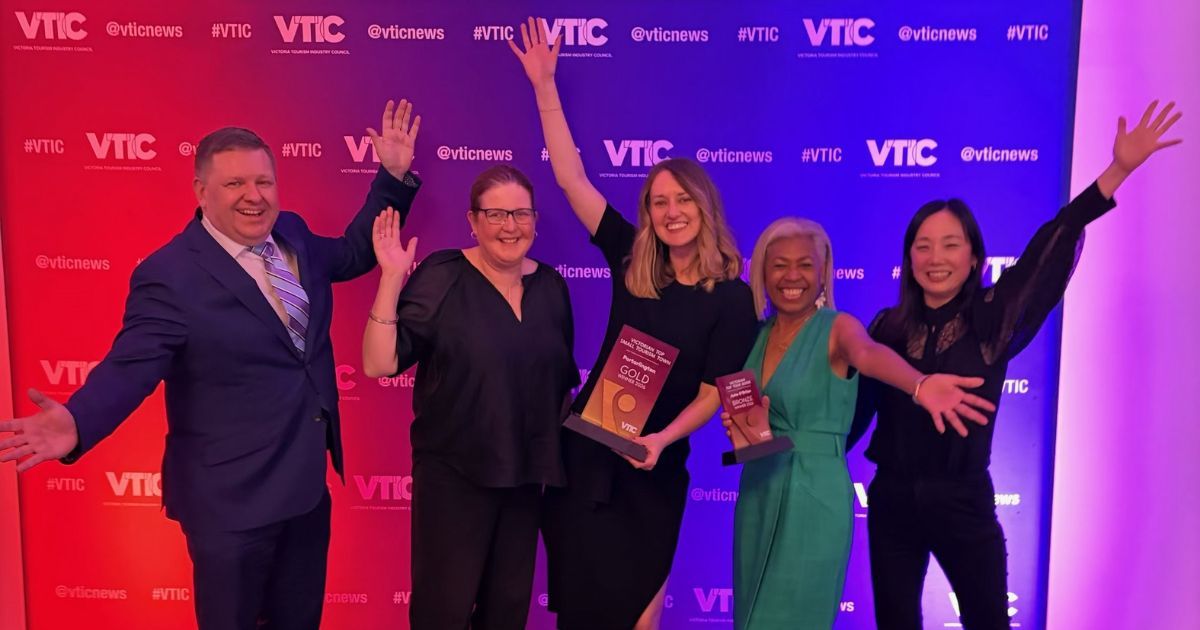 Five people celebrating with awards on a colorful backdrop.