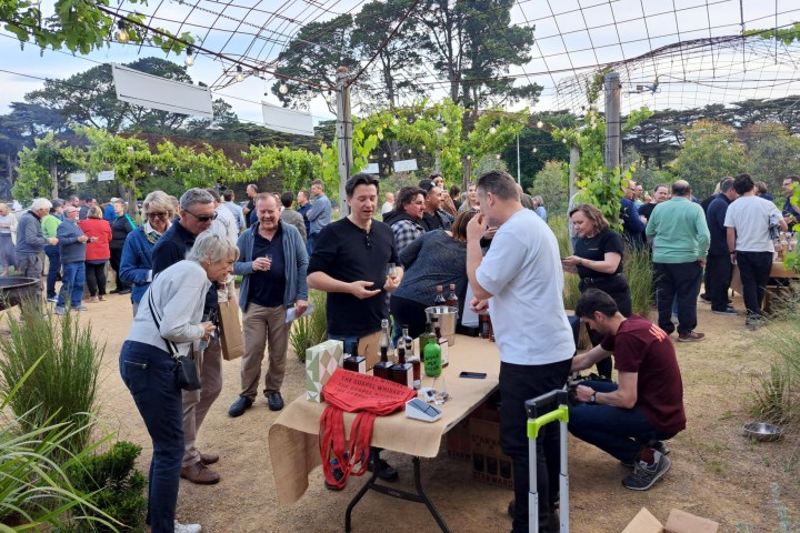 People gathered around a table with drinks at an outdoor event.